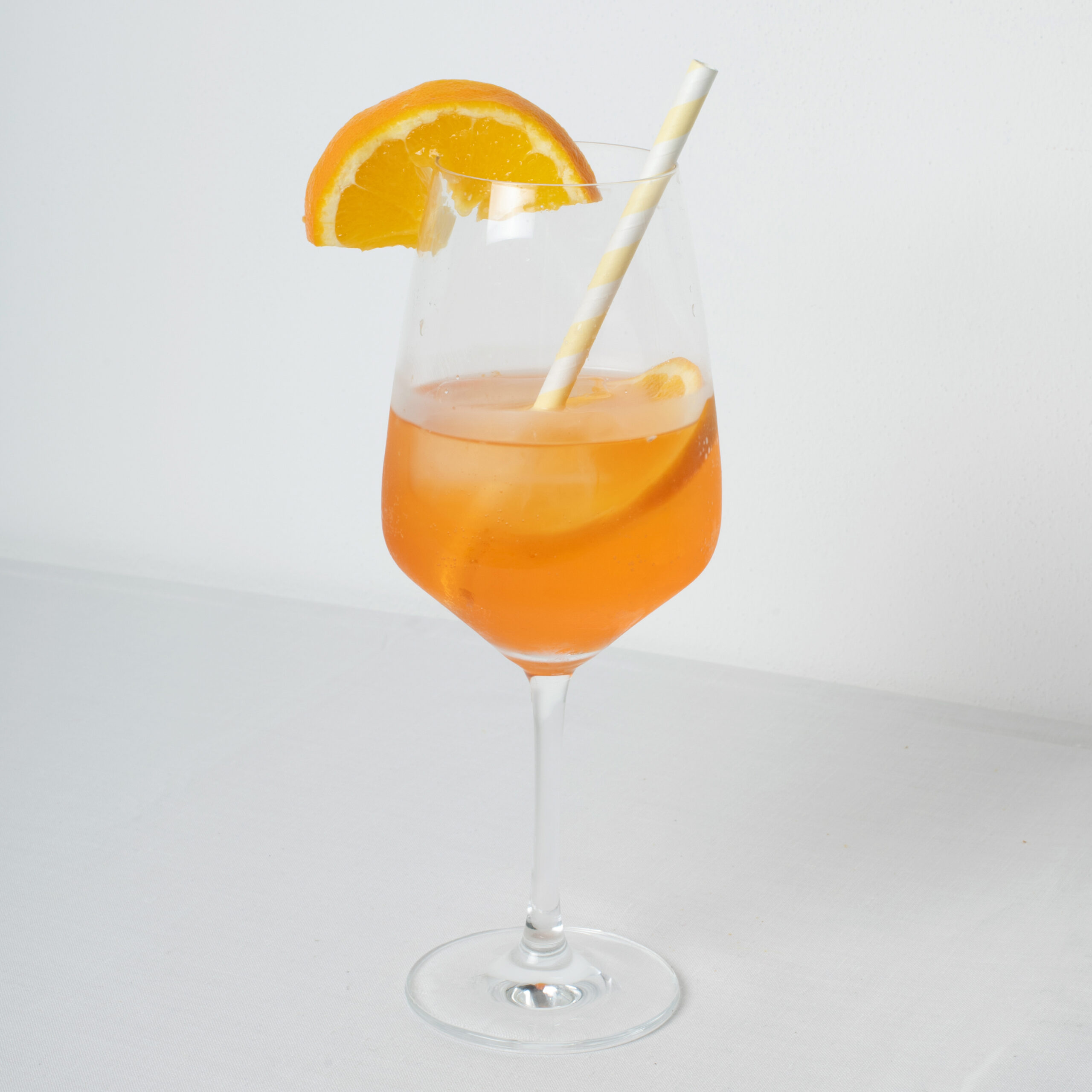 Ein Getränk im Glas mit Strohhalm und Orangenscheibe